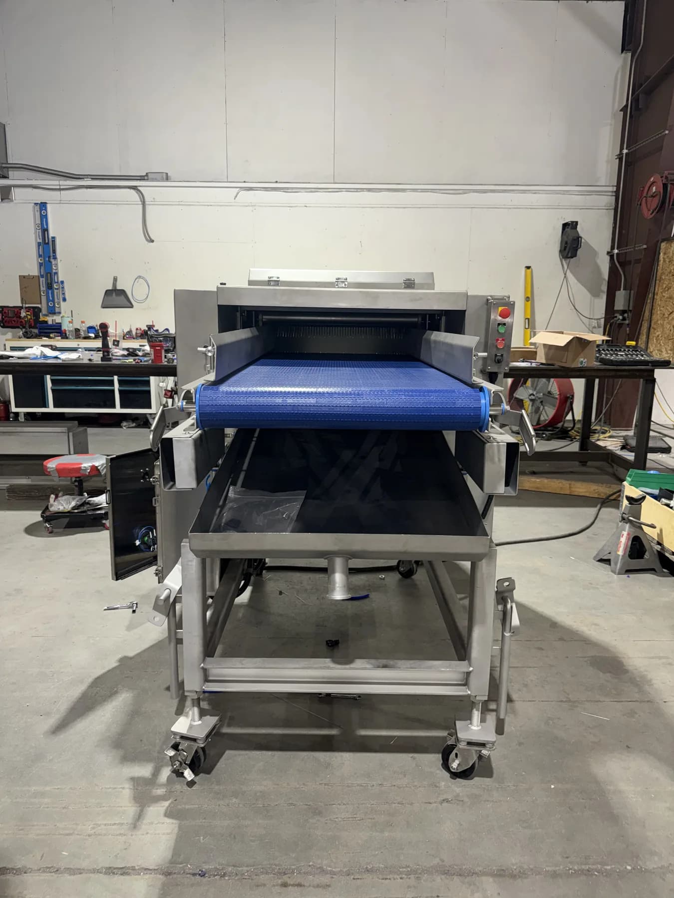 Front view of custom enclosed stainless equipment with blue modular belt and control panel