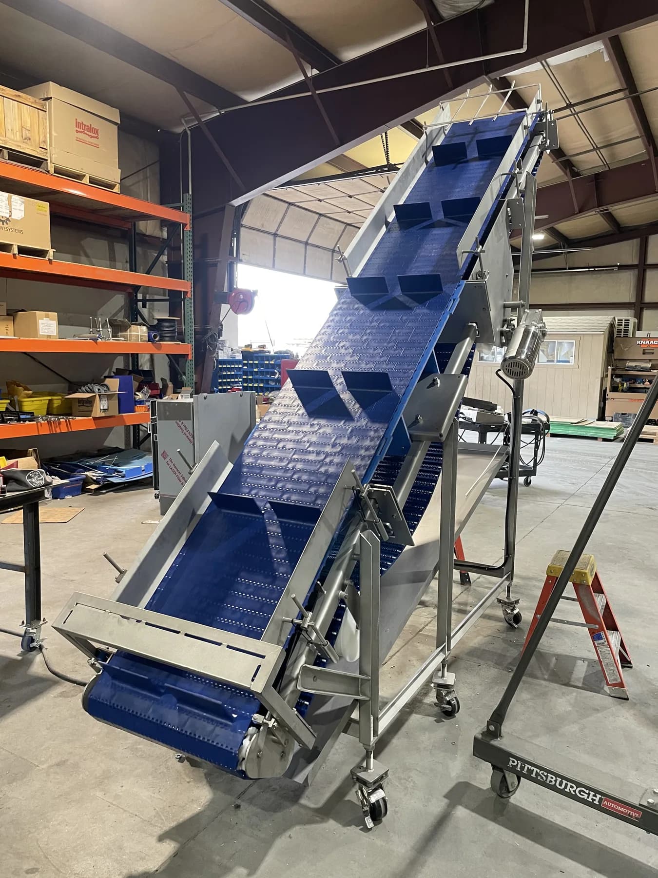 High-angle modular incline conveyor shown from the front-left side