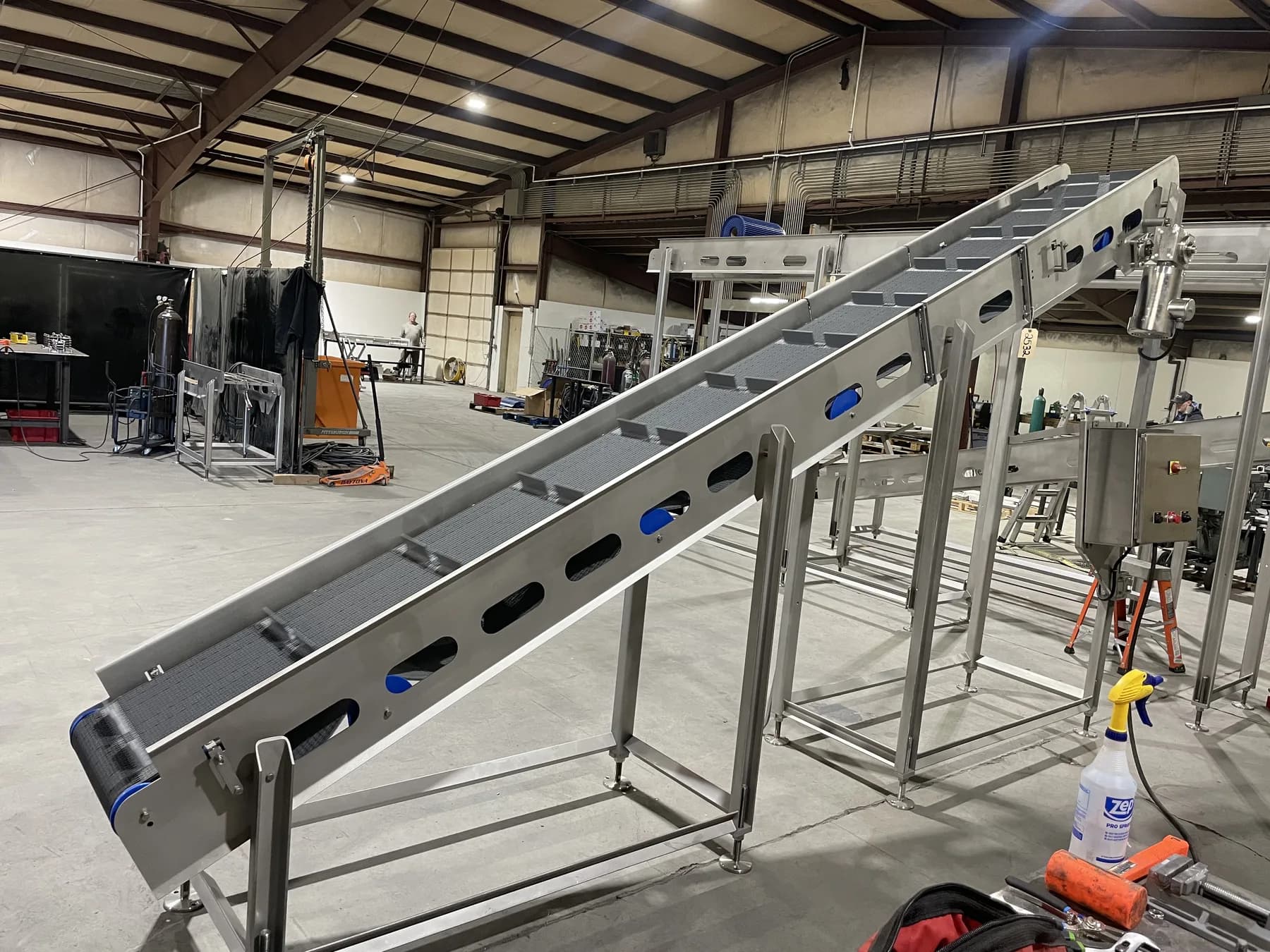 Long stainless incline conveyor shown from the lower end