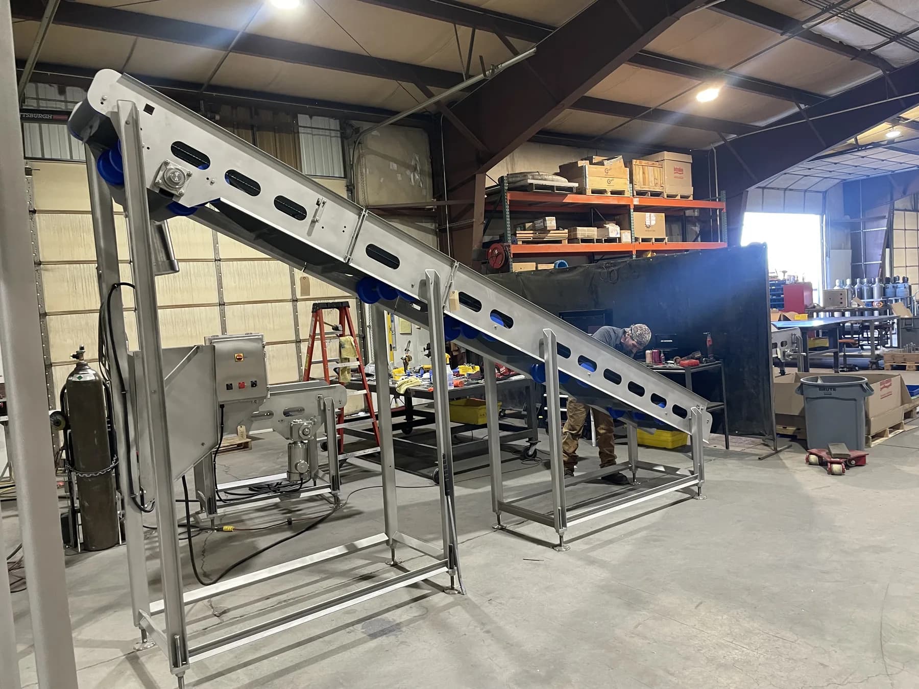 Three-quarter view of stainless incline conveyor and support frame